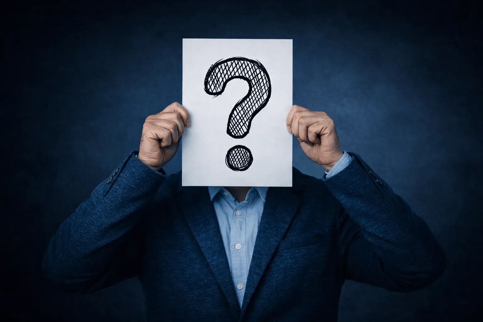 En man håller fram ett stort Frågetecken på vit bakgrund över ansiktet